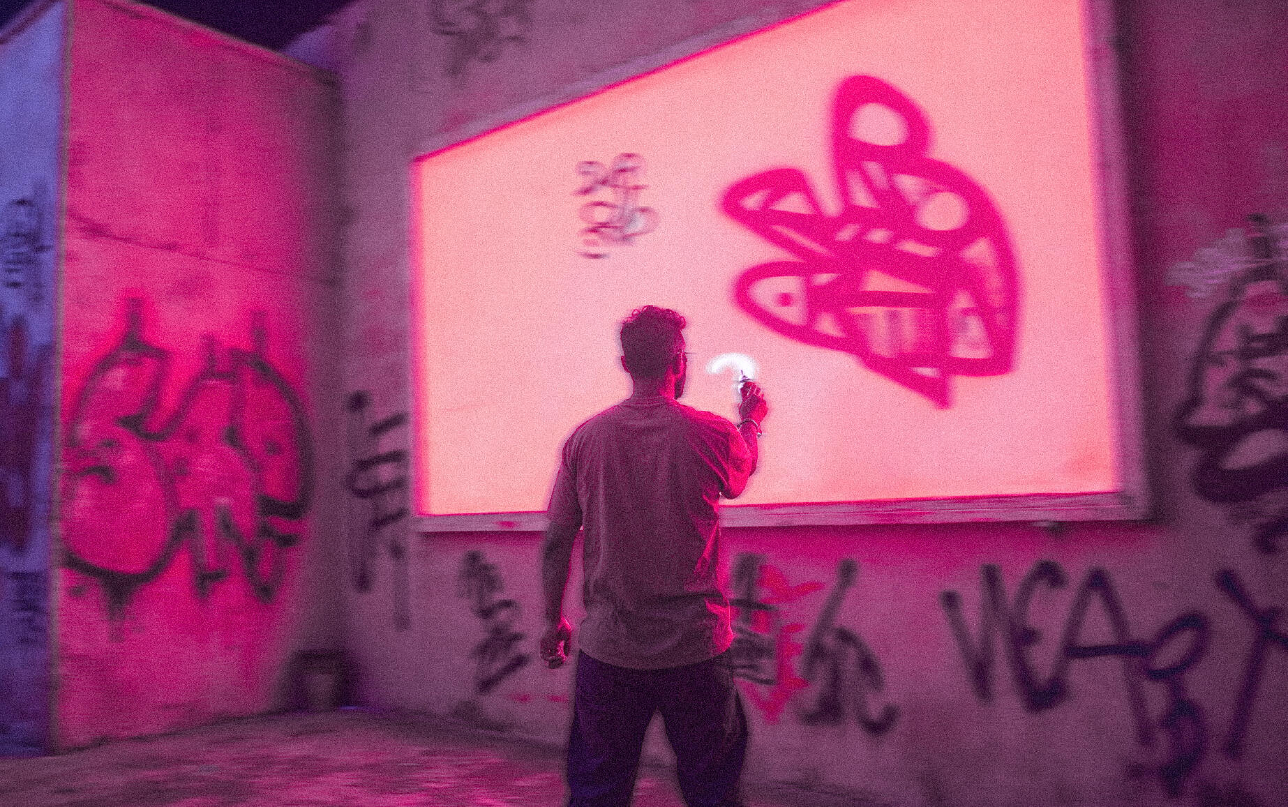 a person spray painting graffiti onto a wall in an urban setting